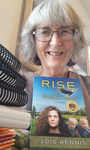 Lois Kennis holds a copy of her book Rise on Eagles' Wings