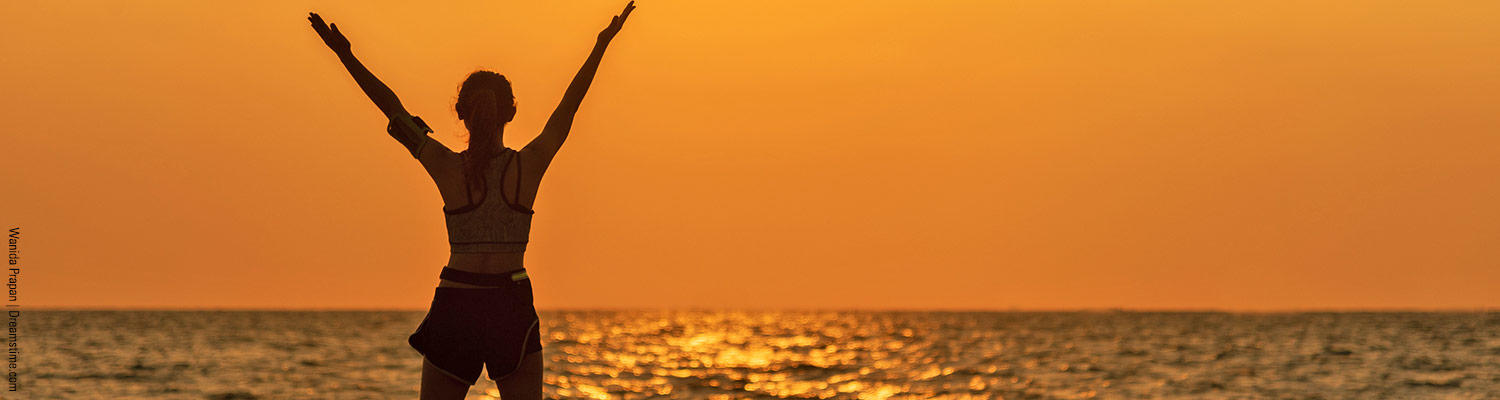 Person with arms outstretched to sunset 